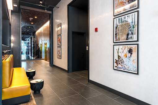 A hallway with a yellow bench and pictures on the wall.