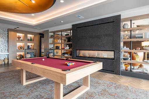 A pool table with a red cloth and a fireplace in the background.