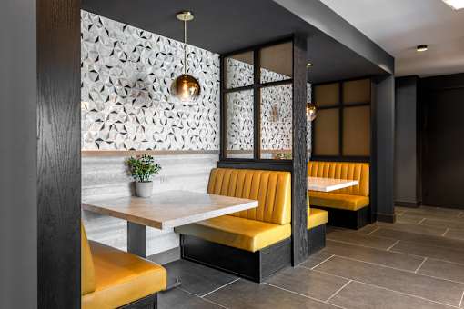 A restaurant interior with a white table and yellow booths.