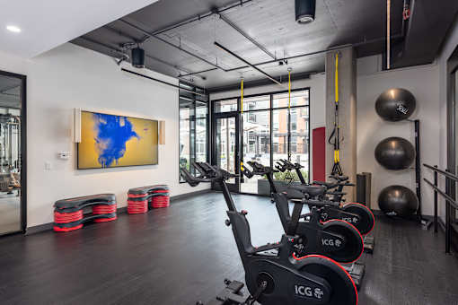 A gym with a row of stationary bikes and a painting on the wall.