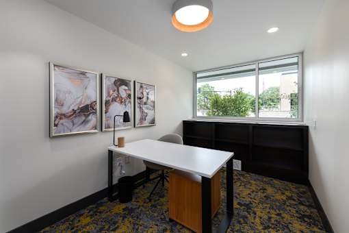 A white desk with a black chair in a room with a window.