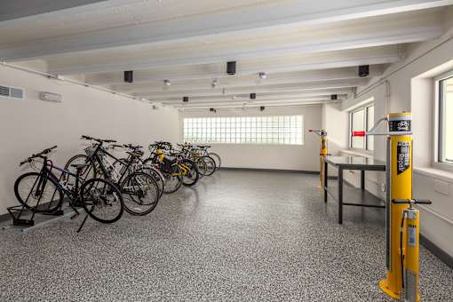A room with a row of bicycles and a yellow pole.