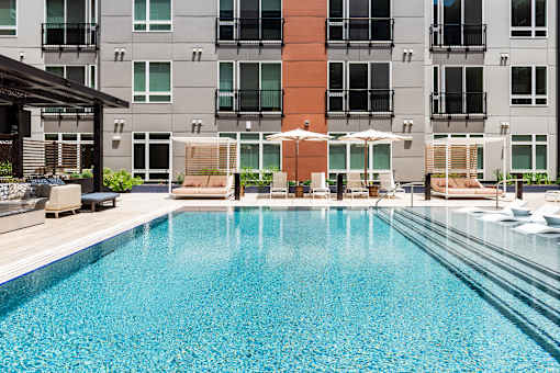 A large swimming pool in front of a multi-story apartment building.