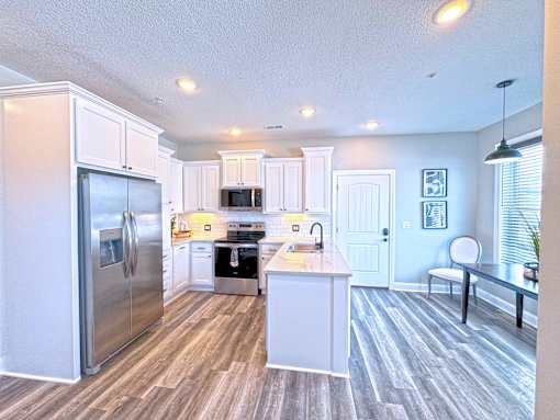 A kitchen with a refrigerator, microwave, oven, and sink.