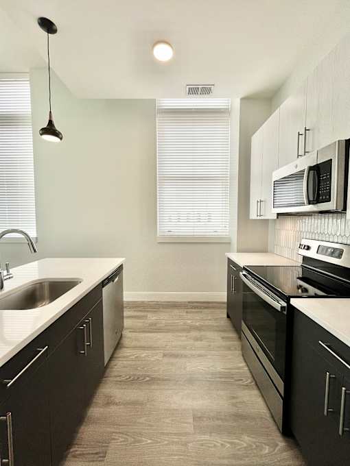 A modern kitchen with dark wood cabinets and a white countertop.