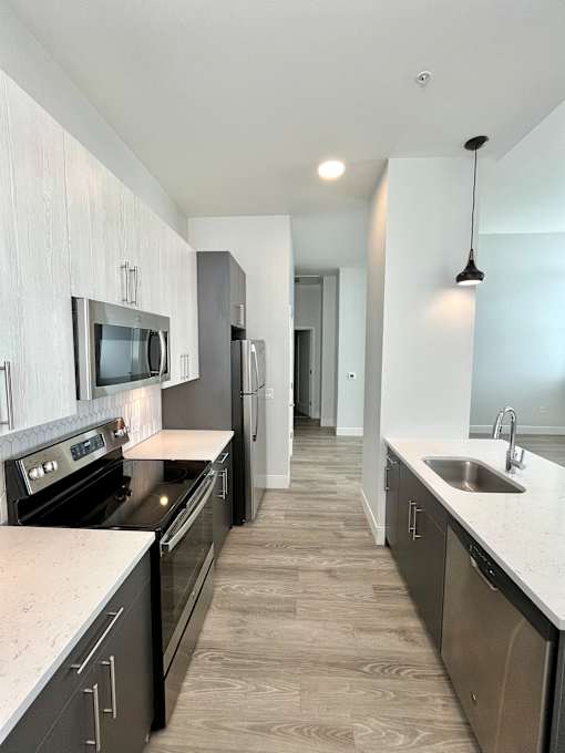 A modern kitchen with dark wood cabinets and stainless steel appliances.