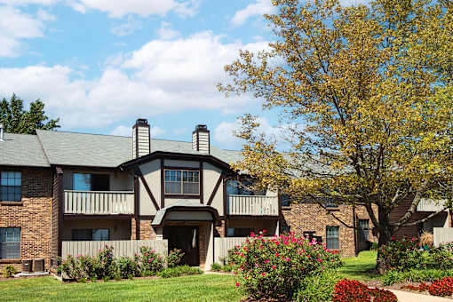 an apartment building with a lawn and flowering plants