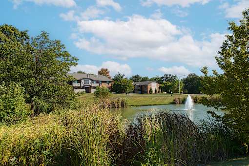 a pond with a fountain and houses in the background