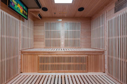 A room with wooden walls and floor and a television mounted on the wall.