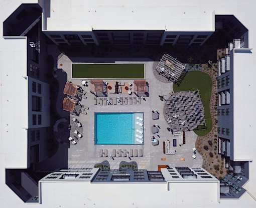 A large swimming pool is surrounded by lounge chairs and umbrellas at Plaza at Pinnacle Hills, Rogers, AR, 72758