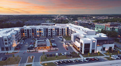 A parking lot is in front of a building with a sunset in the background.