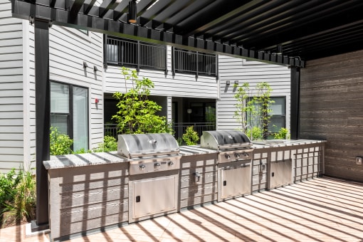 the outdoor kitchen has stainless steel appliances and a bar with grill at The Flats & Terraces at Wildhorse Village, Chesterfield, MO