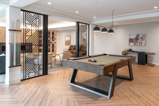 a billiards table in a living room with a glass door at The Flats & Terraces at Wildhorse Village, Missouri, 63005