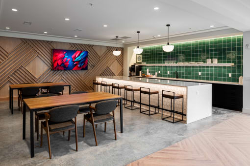 a dining area with a table and chairs and a bar with green tiles at The Flats & Terraces at Wildhorse Village, Chesterfield, Missouri