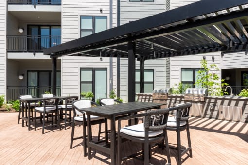 a patio with tables and chairs under an awning at The Flats & Terraces at Wildhorse Village, Chesterfield