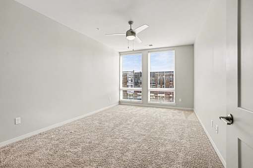 A room with a carpet floor and a ceiling fan.