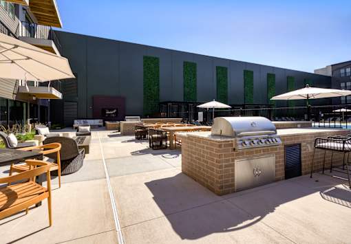 A patio area with tables and chairs and a grill. at The Cunningham Apartments, West Des Moines, IA, 50266