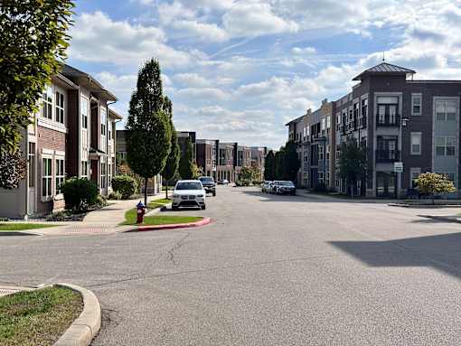 a city street with cars parked in front of buildings at GrandView Flats and Townhomes, Granger, IN