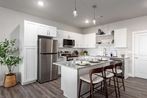 A kitchen with a refrigerator, microwave, and a counter with chairs at Hawk Ridge Apartments, Lake St. Louis, Missouri, 63367