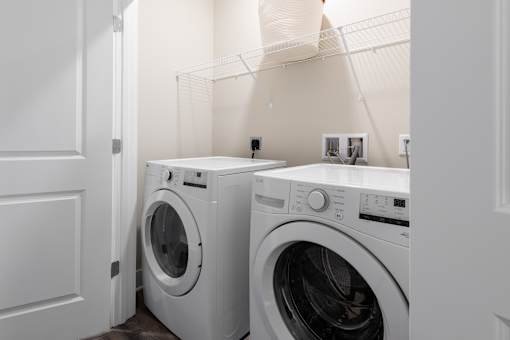 Two white front load washing machines in a laundry room at Hawk Ridge Apartments, Lake St. Louis, MO 63367