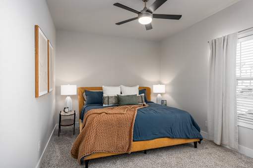 A bedroom with a bed, a ceiling fan, and two lamps at Hawk Ridge Apartments, Lake St. Louis, Missouri 63367