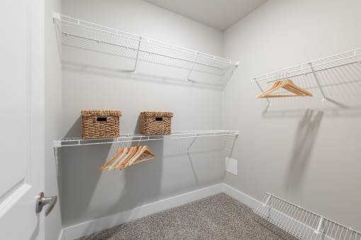 A white closet with a grey carpet and two baskets on the shelf at Hawk Ridge Apartments, Lake St. Louis, 63367