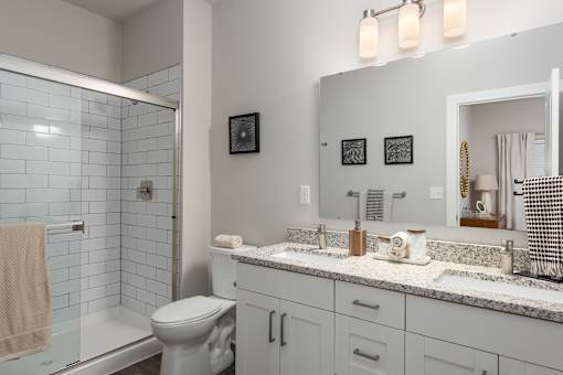 A bathroom with a toilet, sink, and mirror at Hawk Ridge Apartments, Lake St. Louis, MO 63367