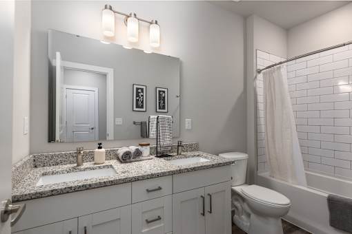 A bathroom with a white toilet, sink, and a white shower curtain at Hawk Ridge Apartments, MO 63367