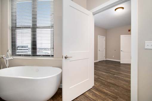 A white bathroom with a tub and a window.