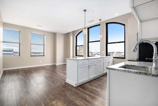 A kitchen with a white counter and cabinets with a view of the city.