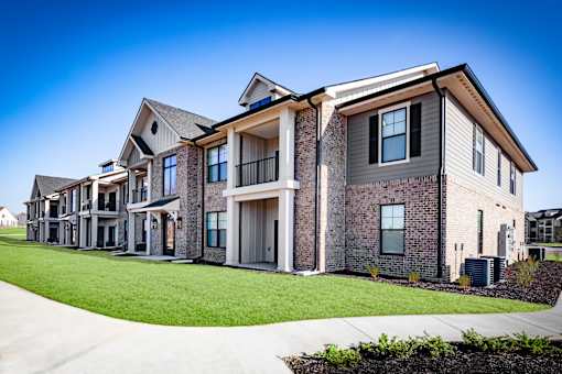 A modern two-story residential building with a mix of stone and siding exterior.