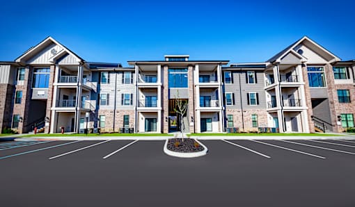 A large apartment complex with a parking lot in front.