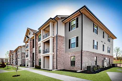 A modern apartment building with a brick facade and multiple balconies.