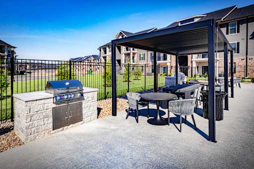 A patio with a grill and a table with chairs.