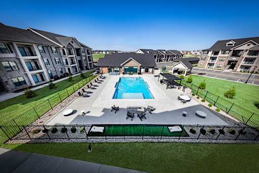 A large swimming pool surrounded by a black fence and a grassy area.