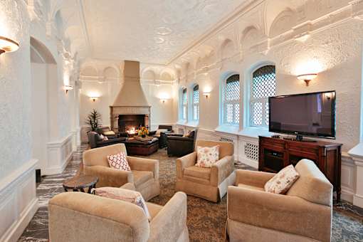 Community room with three white chairs, white walls, and fireplace on far wall at Residences at Forest Park, Saint Louis, MO, 63108