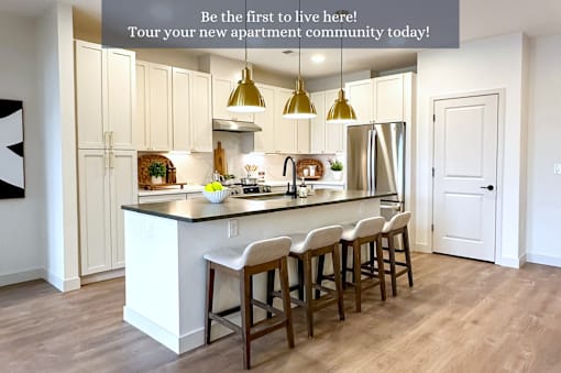 A kitchen with white cabinets and a central island with bar stools.