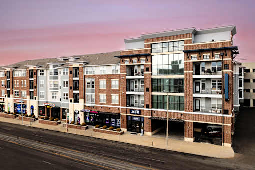 A large multi-story building with a flat roof and a parking lot in front.