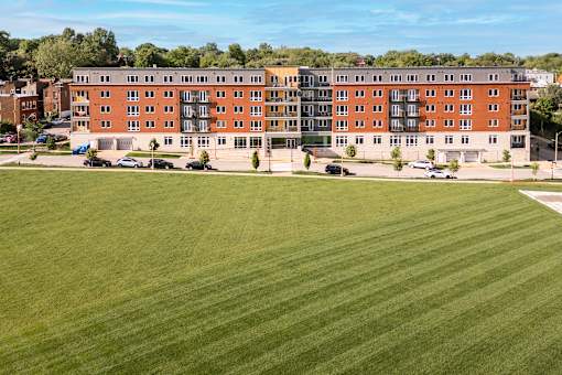 A large grassy field in front of a red brick building.