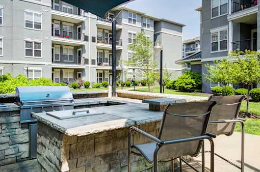 A stone patio with a grill and chair.