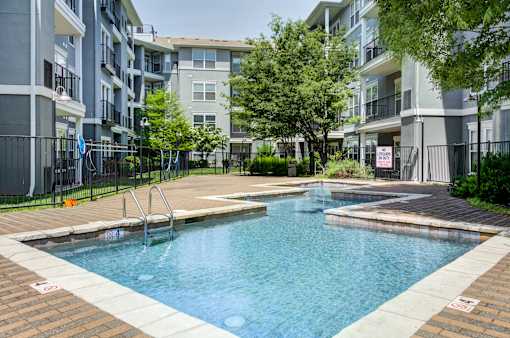 A swimming pool in a residential area surrounded by apartment buildings.