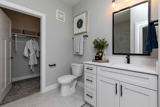 A bathroom with a toilet, sink, and mirror at The Cunningham Apartments, Iowa, 50266