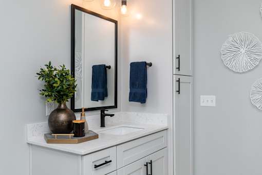 A bathroom with a white countertop and a mirror above it at The Cunningham Apartments, West Des Moines