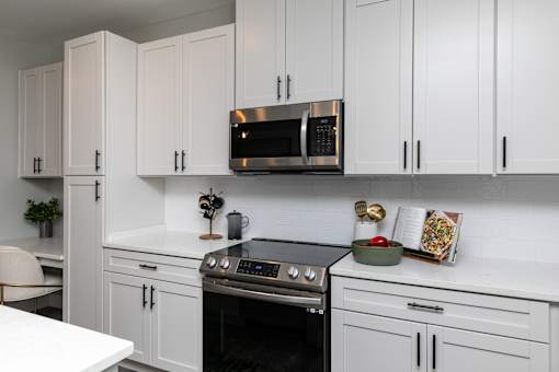 A kitchen with white cabinets and a black oven. at The Cunningham Apartments, West Des Moines