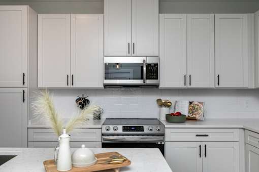 A kitchen with white cabinets and a marble countertop. at The Cunningham Apartments, West Des Moines, 50266