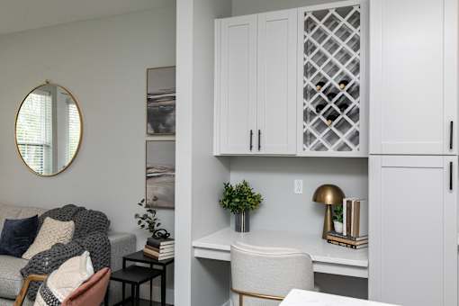 A white chair sits in front of a desk with a lamp on it. at The Cunningham Apartments, Iowa, 50266