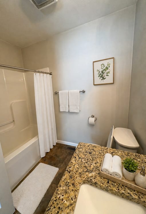 A bathroom with a granite counter top and a white toilet.
