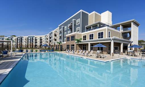 A large swimming pool in front of a multi-story residential building.