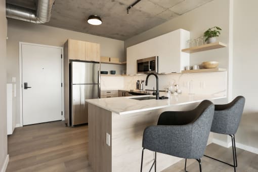 a kitchen with white cabinets and a marble counter top and a stainless steel refrigerator at One Foundry Way, St. Louis, 63110