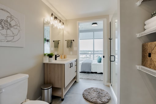 a bathroom with a toilet and a sink and a door to a bedroom at One Foundry Way, St. Louis, MO